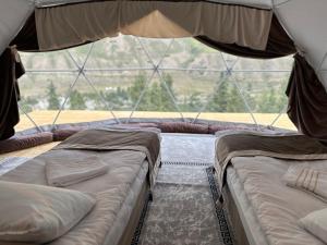 NarynにあるTenir-Too Glampingの大きな窓付きの客室で、ベッド2台が備わります。