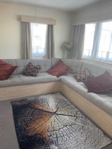 sala de estar con sofá y almohadas en 2 Bedroom Caravan - Ash 51, Trecco Bay, en Newton