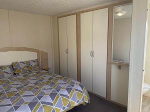 a bedroom with a bed and cabinets and a bathroom at 2 Bedroom Caravan - Ash 51, Trecco Bay in Newton