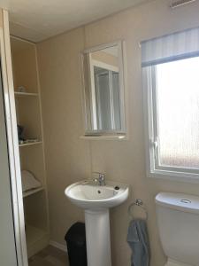 a bathroom with a sink and a toilet and a window at 2 Bedroom Caravan - Ash 51, Trecco Bay in Newton