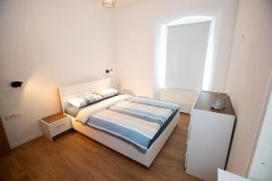 a white bedroom with a bed and a window at Newly adapted 3-room apartment in Postojna
