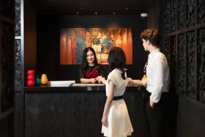 un hombre y una mujer de pie en un bar en The Ember Hotel en Bangkok