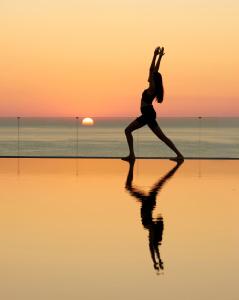 a woman running on the beach at sunset at Minos Palace Hotel & Suites - Adults Only in Agios Nikolaos