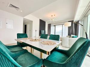 ein Wohnzimmer mit einem Tisch und grünen Stühlen in der Unterkunft Burj Khalifa View! Downtown Dubai in Dubai