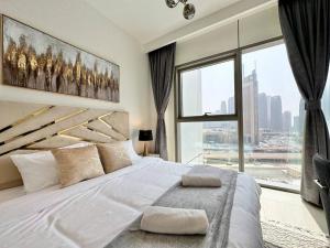 Schlafzimmer mit einem großen weißen Bett und einem großen Fenster in der Unterkunft Burj Khalifa View! Downtown Dubai in Dubai