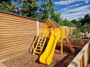 a playground with a yellow slide next to a fence at Šport center Prodnik in Ljubno