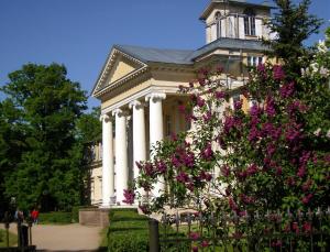 un gran edificio blanco con columnas y flores rosas en Krimuldas Muiža, en Sigulda
