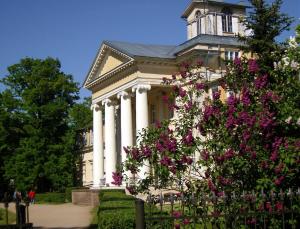 un gran edificio blanco con columnas y flores rosas en Krimuldas Muiža en Sigulda