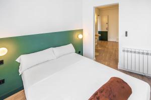 1 dormitorio con cama blanca y pared verde en AngelitoMAD, en Madrid