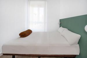 1 dormitorio con cama blanca y ventana en AngelitoMAD en Madrid