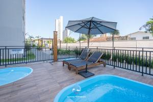a hot tub with a bench and an umbrella at Apartamento com VISTA MAR, Ar-condicionado, Wi-Fi Condomínio com PISCINA, quadra de esportes Playground infantil a 15 minutos do Beto Carreiro in Piçarras