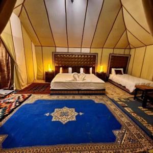 Luxury Desert Camp Merzouga في مرزوقة: غرفة نوم بسرير وسجادة زرقاء في خيمة
