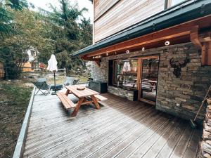 eine Holzterrasse mit einem Picknicktisch neben einem Gebäude in der Unterkunft Le Peyra, Apt 4 personnes avec terrasse et jardin in Le Monêtier-les-Bains