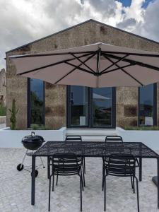 une table et des chaises sous un grand parasol dans l'établissement Modern and spacious Cork House with private valley view, à Caldas da Rainha