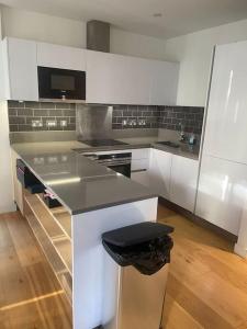 a kitchen with white cabinets and a black counter top at Luxurious NEW 2 Bed apartment in London