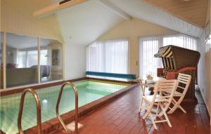 ein Pool mit einem Tisch und Stühlen daneben in der Unterkunft Awesome Home In Hvide Sande With Indoor Swimming Pool in Hvide Sande