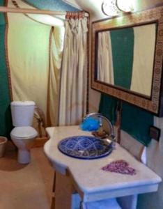 a bathroom with a sink and a toilet and a mirror at Luxury Desert Camp Merzouga in Merzouga