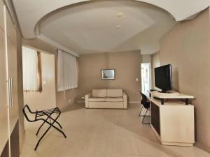 a living room with a television and a couch at Hotel Metrópole Maringá in Maringá