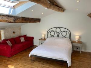 1 dormitorio con 1 cama y 1 sofá rojo en La Ruche, en Theil-Rabier