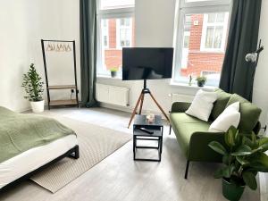 a living room with a green couch and a tv at ENDLESS: Studio mit Netflix + Workstation im Zentrum in Schwerin