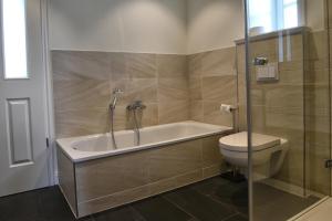 a bathroom with a bath tub and a toilet at Huus Leeftalich in Alkersum +18 photos