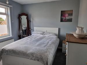 1 dormitorio con cama, mesa y espejo en 31 Elwyn Road en March