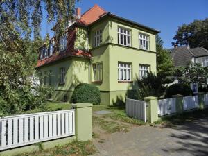an old yellow house with a white fence at Strandstraße 60 Ferienwohnung S14 in Graal-Müritz