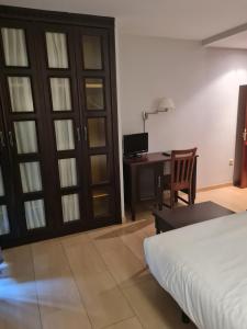 a bedroom with a bed and a desk with a computer at Hotel Restaurante Ribera del Chicu in Arriondas