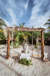 a sign on a beach with a statue in the sand at Namaste Beach Club & Hotel in Tierra Bomba