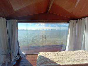 Schlafzimmer mit einem großen Fenster mit Blick auf das Wasser in der Unterkunft ILHA DA FANTASIA in Belém