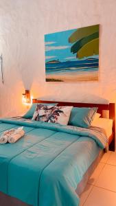 a bedroom with a blue bed with a painting on the wall at Olho D'Água Pousada in Guaramiranga