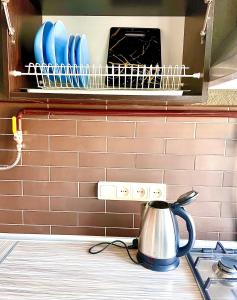 eine Küchentheke mit einem Wasserkocher und Geschirr in einem Wäscheständer in der Unterkunft Квартира Сапфір Avenue Myru 35a in Tschernihiw
