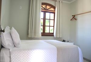 a bedroom with a white bed and a window at POUSADA CAPIM LIMÃO in Diamantina