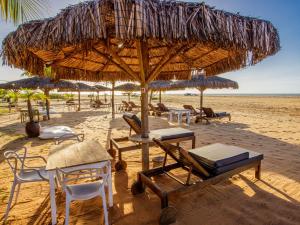 a beach with chairs and tables and a straw umbrella at Pousada Mi Secreto in São Miguel do Gostoso