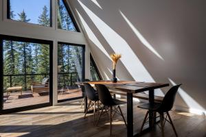 a dining room with a table and chairs and large windows at New Modern Rustic A-Frame Cabin with Barrel Sauna in Nordegg