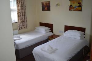 two beds in a hotel room with white sheets at Oak house hotel in Wellingborough