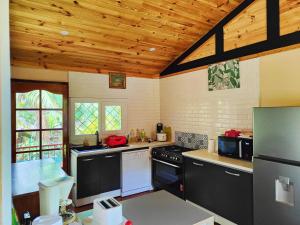 a kitchen with black appliances and a wooden ceiling at Chalet Combava in Saint-Benoît