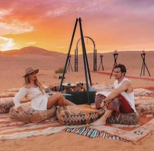 メルズーガにあるDesert Berber Campの砂漠の毛布に腰掛けた男女