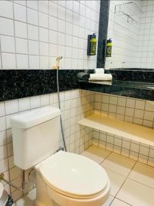 y baño con aseo blanco y espejo. en Ponta negra Flat, en Natal