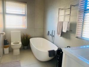 a white bathroom with a tub and a toilet at Rosebud 4 Beacon Point in Mossel Bay