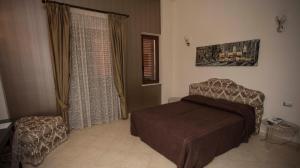 una camera con letto e sedia di Regalpetra Hotel a Racalmuto