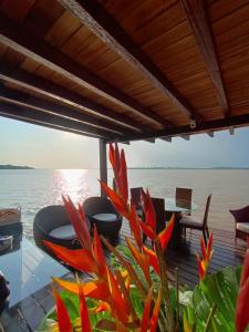 a deck with a table and flowers on the water at SUITE BANGALÔ ILHA Da FANTASIA in Belém
