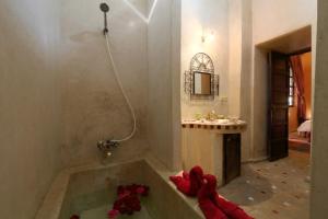 a bathroom with a bath tub with red flowers in it at Riad en Exlusivité à 5min de la place jamaa el fna in Marrakesh