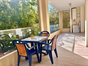 a blue table and chairs in a room with a large window at Alghero CHARMING APARTMENTS DOWNTOWN in Alghero