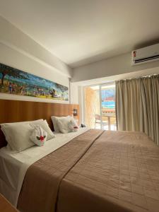 a bedroom with a large bed with a large window at Pipas Bay in Pipa