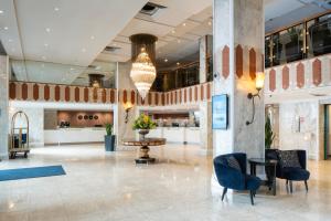 eine Lobby mit Stühlen, einem Tisch und einem Kronleuchter in der Unterkunft Danubius Hotel Regents Park in London