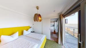 a bedroom with a bed with a yellow headboard and a balcony at Speicher Residenz Barth E6 App 1 in Barth