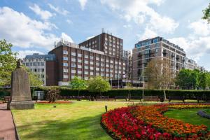 a park with flowers in front of buildings at Danubius Hotel Regents Park in London