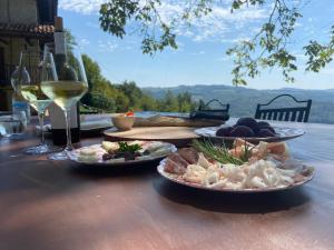 een tafel met drie borden eten en glazen wijn bij Cascina Manzoni appartamenti in Bossolasco