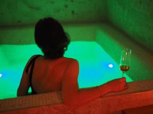 Dimore dei Mercanti في ماتيرا: امرأة تجلس في حوض الاستحمام مع كوب من النبيذ